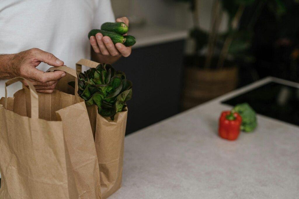 A person placing fresh vegetables into a paper bag on a kitchen counter. Vibrant and healthy organic ingredients.